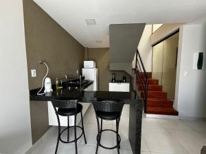 a kitchen with a black counter and bar stools at Residencial Quinta Lusa em Cond. Valle do Sal - Pox. Gav Resort e Aqualnd - Casas mobilhadas, confortáveis e seguras para passar momentos maravilhosos no Atalaia.. in Salinópolis +2 photos