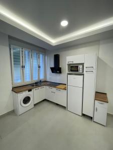 eine Küche mit weißen Schränken und einer Waschmaschine und einem Trockner in der Unterkunft Luxury apartment Bella Málaga in Málaga