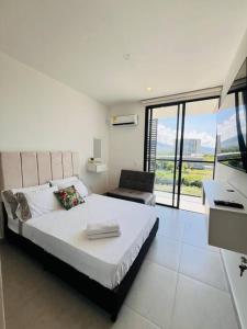 ein weißes Schlafzimmer mit einem Bett, einem Schreibtisch und einem Fenster in der Unterkunft Nuevo apto familiar cerca al mar in Santa Marta