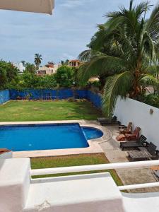 una piscina junto a un patio con una palmera en Casa Garzas 34, en Rincón de Guayabitos