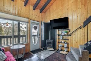 a living room with a tv and a wood wall at Brian Head Condo Walk to Giant Steps Ski Lifts! in Brian Head