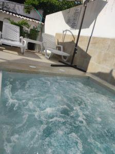 a pool of water with chairs and an umbrella at Apartamentos Villa Leonor in Coveñas