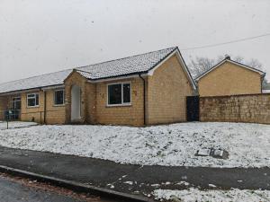 a brick house with snow on the ground at 2 Bedroom Cotswold Bungalow in Castle Combe