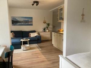 a living room with a blue couch and a kitchen at Klein&Fein-Stadtnahes Apartment in Celle