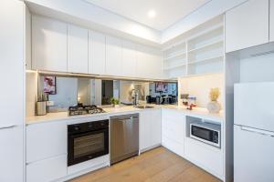a kitchen with white cabinets and stainless steel appliances at Modern 2B2BA Apartment in the Heart of Bankstown in Bankstown