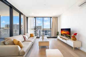 a living room with a couch and a tv at Modern 2B2BA Apartment in the Heart of Bankstown in Bankstown