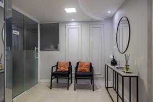 a bathroom with two chairs and a table and a mirror at Ed. Acácias B in Balneário Camboriú