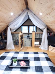 a room with a bed with a checkered floor at Couples Getaway Cabin with a Loft Bed - Firepit - Creek Access in Dahlonega