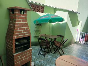 a patio with a table with an umbrella and a brick oven at Cantinho da Bethânia in São Pedro da Aldeia