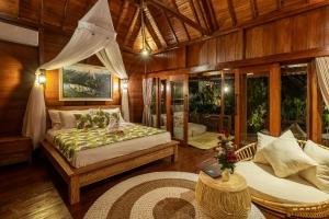 un dormitorio con una cama y un sofá en Anantra Bali Eco Villa, en Ubud