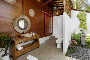 un baño con inodoro y espejo en Anantra Bali Eco Villa, en Ubud 98 fotos más
