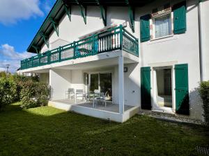 a white house with a balcony with a table and chairs at BaskoParadis I Apt I Central I Calme I Lumineux I Lit 160 I Terrasse I Jardin in Cambo-les-Bains