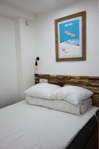 - un lit avec deux oreillers et une photo sur le mur dans l'établissement Résidence Menandiere - APPARTEMENT 2 PIECES- ALPE D'HUEZ CENTRE STATION MAE-3581, à Huez