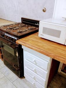 a kitchen with a stove and a microwave on a counter at Casita del Centro in San Clemente del Tuyú