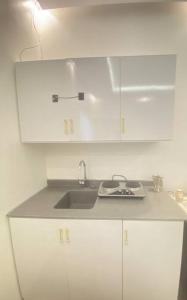 a kitchen with a sink and white cabinets at شقة غرفة نوم وصالة دخـول ذاتـي in Al Kharj