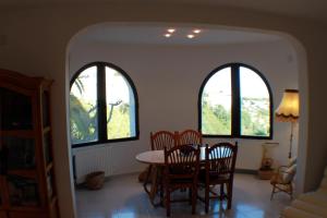 comedor con 2 ventanas arqueadas, mesa y sillas en Luz - holiday apartment in peaceful surroundings in Benissa, en Benissa