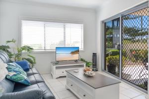 a living room with a couch and a tv at Sunrise on Terrace Unit 3, 21 Terrace Street Evans Head in Evans Head