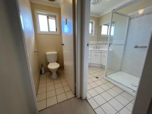 a bathroom with a toilet and a glass shower at Whispering Pines Unit 3, 7 Waratah Lane Evans Head in Evans Head +3 photos