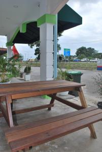 um banco de madeira sentado sob um guarda-chuva numa estação de serviço em Apple Inn Hotel em Sungai Petani