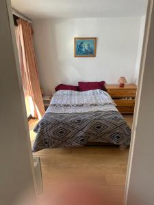 een slaapkamer met een bed met een deken en rode kussens bij La montagne in Villarembert