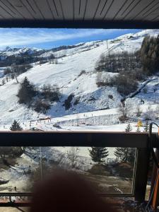 een raam met uitzicht op een met sneeuw bedekte skipiste bij La montagne in Villarembert