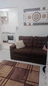 a living room with a brown couch in a room at Apartamento Canto do Forte in Praia Grande