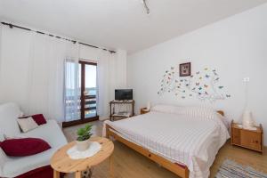 a white bedroom with a bed and a couch at Apartment Mili in Betina