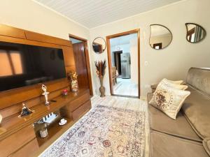 a living room with a couch and a flat screen tv at Casa Conforto 8 min do centrinho in Campos do Jordão +15 photos
