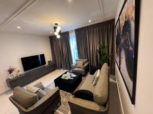 a living room with a couch and chairs and a television at Gem of Loxwood in Accra