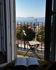 a book on a bed with a view of the ocean at Apartamento Miracies in Vigo