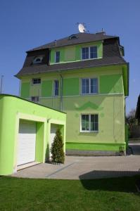 uma grande casa verde com uma garagem branca em Pension Rak em Karlovy Vary