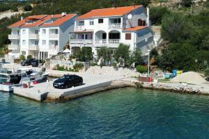 a house with a car parked on a dock in the water at Apartments by the sea Zaglav, Dugi otok - 8134 in Sali