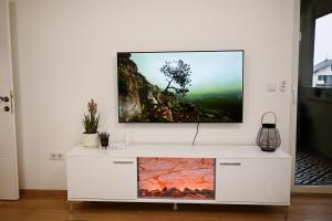 a living room with a tv on a white entertainment center at Modern Apartment MOMENT in Brčko