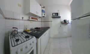 a white kitchen with a stove and a sink at Departamentos Falucho 3 in Santa Rosa