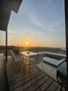 ein Tisch und Stühle auf einer Terrasse mit Sonnenuntergang in der Unterkunft Don Amado in La Bocana