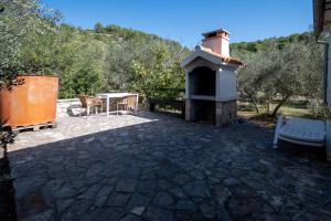 a patio with a table and a fireplace at Secluded fisherman's cottage Cove Dragnjevica - Telascica, Dugi otok - 19966 in Sali +8 photos