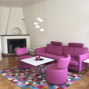 a living room with a purple couch and two pink chairs at Västerviks Citylägenhet in Västervik