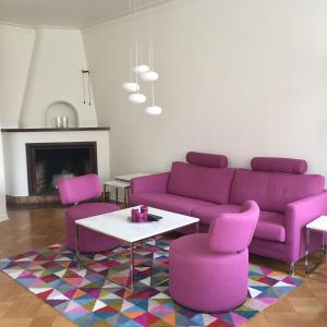 sala de estar con sofá púrpura y 2 sillas rosas en Västerviks Citylägenhet, en Västervik