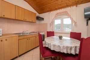 eine Küche mit einem Tisch mit roten Stühlen und einem Waschbecken in der Unterkunft Apartments by the sea Zaglav, Dugi otok - 23204 in Sali + 15 Fotos