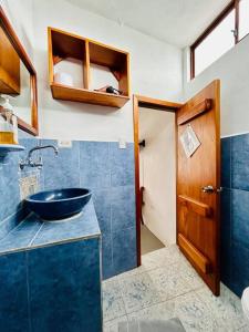 baño con lavabo azul y puerta de madera en Suite con acceso a terraza vista a la Bahia, en Puerto Ayora