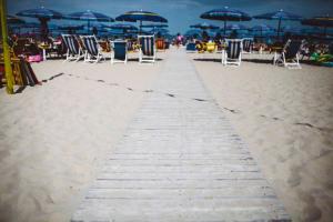 a wooden path on the beach with chairs and umbrellas at Hotel Royal in Giulianova