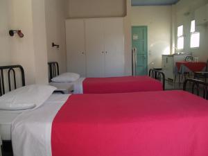 a room with three beds with red and white sheets at Hotel Cavo Mytikas in Mitika