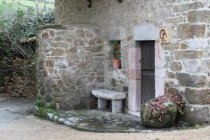 un edificio de piedra con un banco junto a una puerta en Ca María Santa, en Proaza