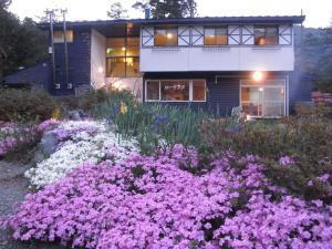 a garden with purple flowers in front of a house at ペンションローザンヌ in Fujikawaguchiko