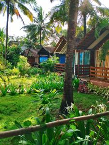 a house in a garden with a palm tree at Lamarine Morjim Beach cottages in Old Goa