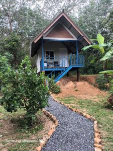 a small house with a blue porch and a gravel path at PhaluayCamping in Koh Phaluai