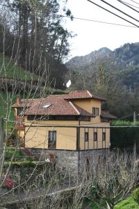 una casa amarilla con techo rojo en Ca María Fayas en Proaza