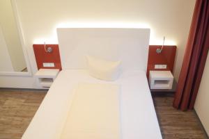 ein weißes Bett in einem Zimmer mit Spiegel in der Unterkunft Hotel Arts in Sankt Leon-Rot