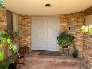 a white front door of a home with plants at Waterside Hideaway in Mandurah