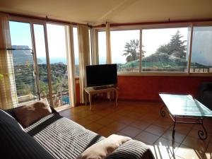 een woonkamer met een bank, een tv en ramen bij T3 vue mer exceptionnelle in Cassis